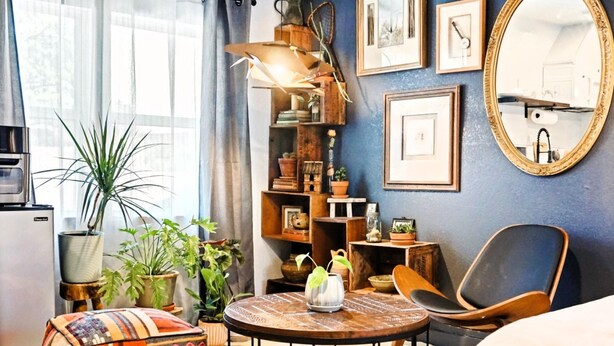 Ein gemütliches Wohnzimmer mit einem runden Holztisch, einem bequemen Sessel und einer Bücherwand voller Bücher und Dekorationsgegenständen.