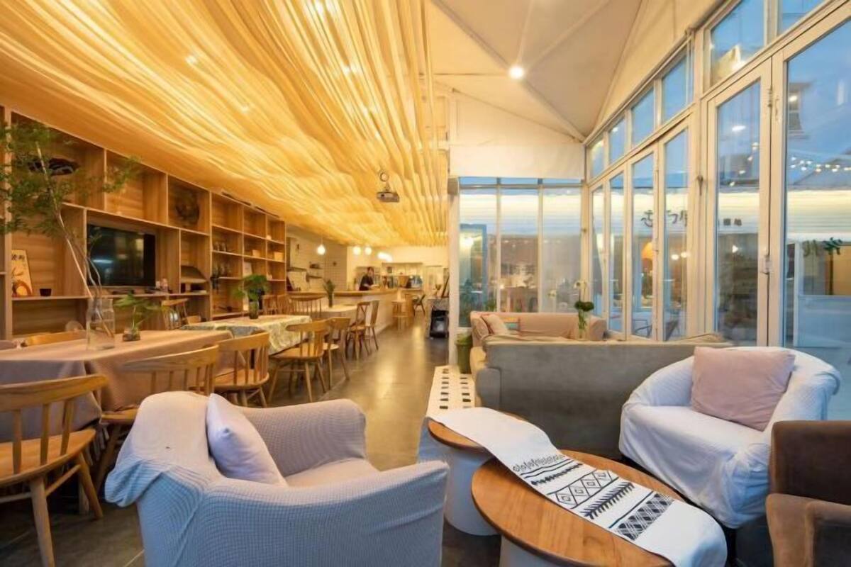 A modern interior with wooden panel ceilings, a dining area, and seating with a view.