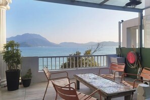 A balcony with a table and chairs, overlooking a body of water and mountains. - Yinyu Meishe Wangbulao B&B (Talang Square Branch) (Shenzhen)
