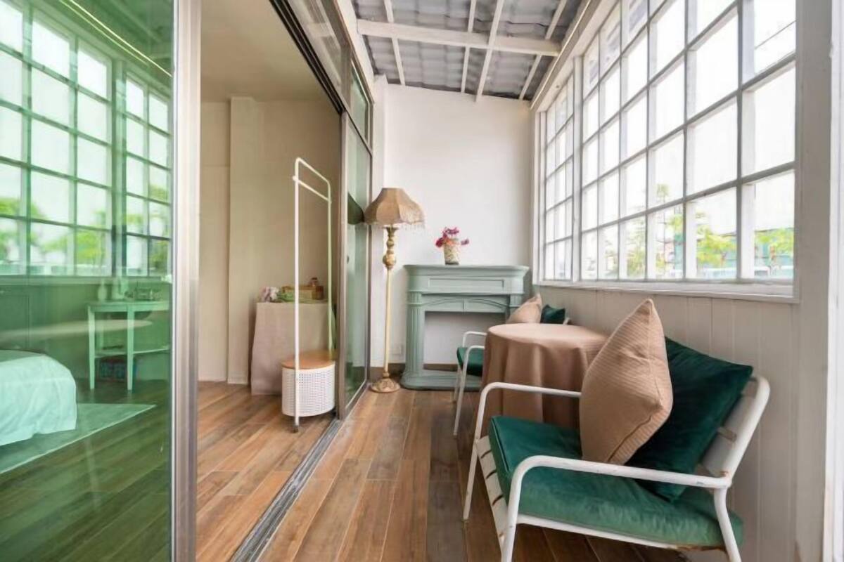 A room with a bed, a sofa, a small table, a lamp, and a fireplace.