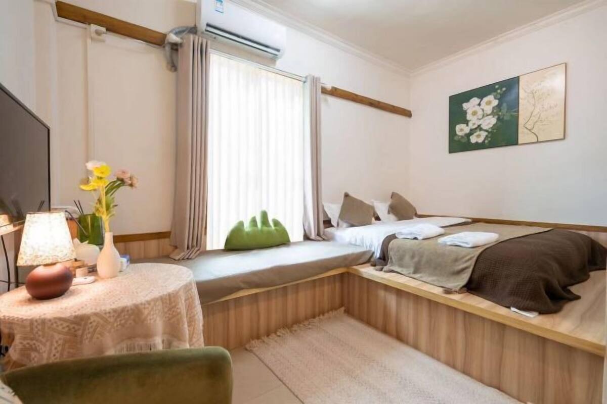 A compact bedroom with a bed, bedside table, lamp, and a window with curtains.