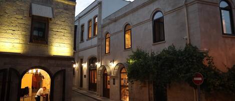 A narrow street with buildings featuring arched windows and a cobblestone path.