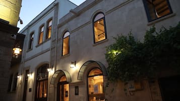 A building with arched windows and doors, a visible sign, and a light fixture on the exterior wall.
