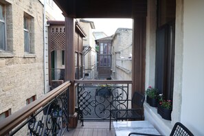Un balcon avec une balustrade en bois, une chaise en métal et des plantes en pot.