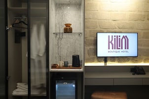 Een hotelkamer met een minibar, een koffiezetapparaat, een schaal en een televisie waarop de naam van het hotel staat.