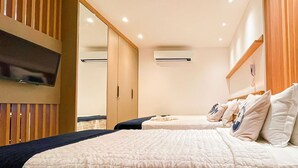 Habitación de hotel con una cama grande, televisor montado en la pared y cabecero de madera.