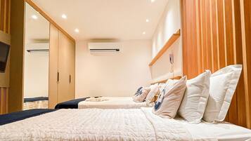 Habitación de hotel con una cama grande, televisor montado en la pared y cabecero de madera.