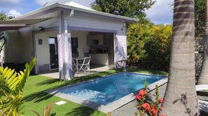 Une maison avec une piscine, un patio couvert et un coin cuisine.