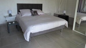 Ein Schlafzimmer mit einem Bett, zwei Nachttischen, einem Schminktisch und einem Vorhang.
