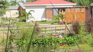 A house with a red roof, surrounded by a garden with a pond and various plants. - Ecolodge Barbuda - Natural Pool & Beach (Saint-François)