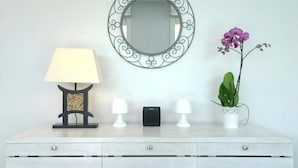 A white dresser with a mirror, two white lamps, a small black speaker, and a potted orchid. - Villa the Lodge - Lagon Saint-françois (Saint-François)