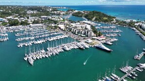 An aerial view of a marina with numerous boats docked, surrounded by buildings and greenery. - Villa Clara (Le Gosier)