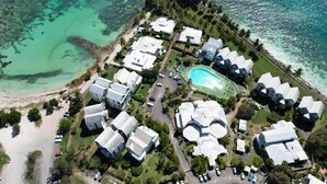 An aerial view of a coastal resort with multiple bungalow-style buildings, a swimming pool, and a beach. - Villa Clara (Le Gosier)