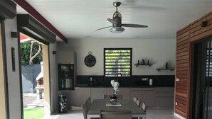 A modern kitchen with a dining area, a ceiling fan, and a view of the outdoors. - Villa Ambre (Saint-François)