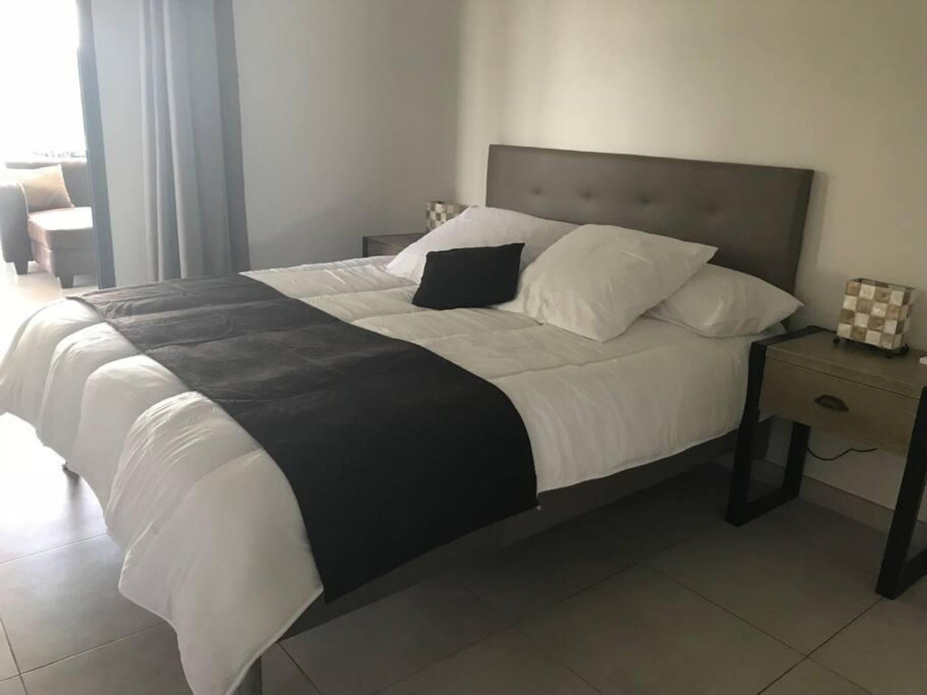 A modern hotel room with a large bed, a bedside table, and a nightstand.