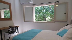 A bedroom with a bed, a desk, and a chair. There are windows with views of trees. - Ecolodge Saba - Natural Pool & Beach (Saint-François)