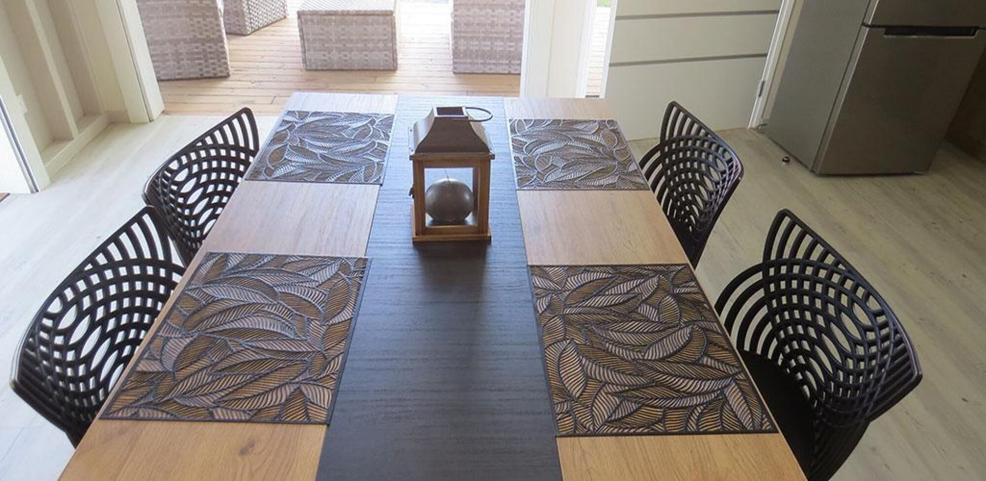 Una mesa de comedor con una lámpara colgante en el centro, rodeada de sillas con elaborados respaldos.
