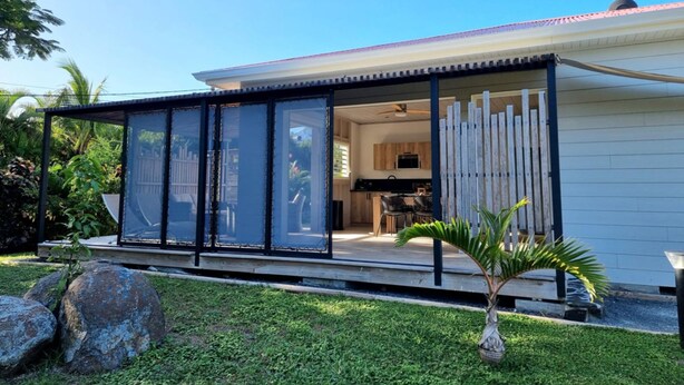 A modern house with a covered patio, a visible kitchen, and a well-maintained lawn. - Ecolodge Saba - Natural Pool & Beach (Saint-François)