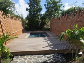 A wooden deck with a pool, surrounded by a bamboo fence and tropical plants. - Ecolodge Anguila - Natural Pool & Beach (Saint-François)