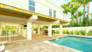 A poolside area with a covered patio, outdoor furniture, and a view of a building with a balcony. - 5 Beautiful 4 Bed 3 Bath Pool Home w Free Dock (Marathon)