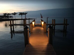 Guests can enjoy a serene waterfront view from the pier, surrounded by palm trees and American flags.