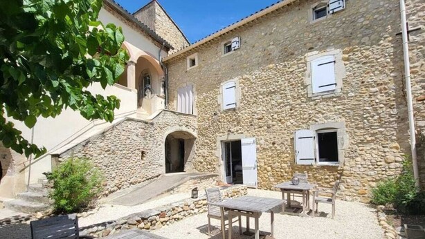 Un edificio de piedra con un patio, asientos al aire libre y una escalera que lleva a un nivel superior.