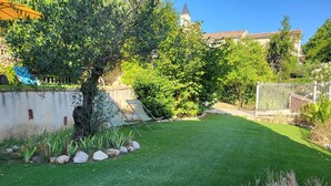 Un jardín bien cuidado con césped, un árbol y un muro de piedra.