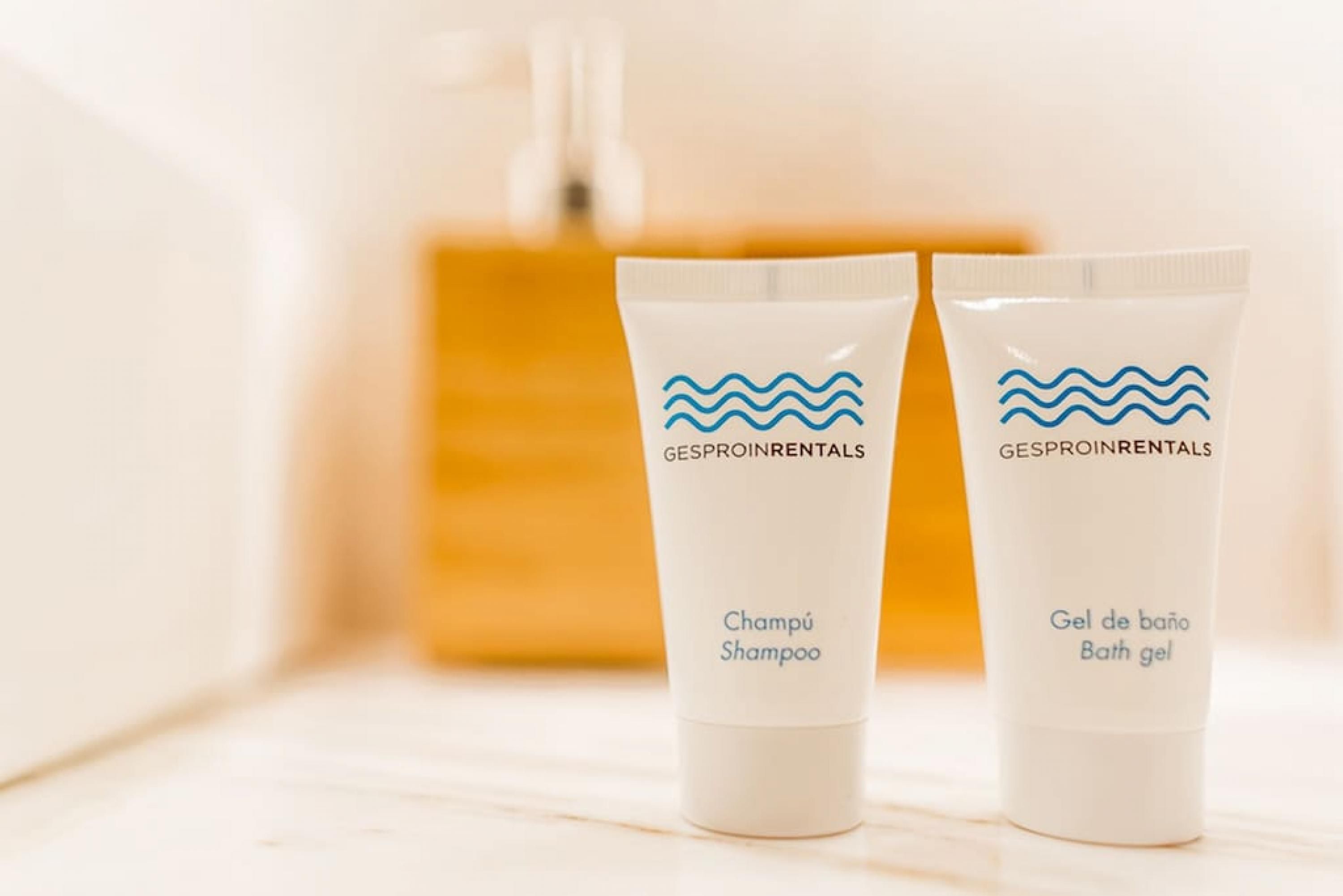 Dos botellas de champú y gel de baño con la marca 'GESPROINRENTALS' sobre una superficie de madera.