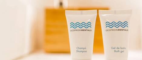 Dos botellas de champú y gel de baño con la marca 'GESPROINRENTALS' sobre una superficie de madera.