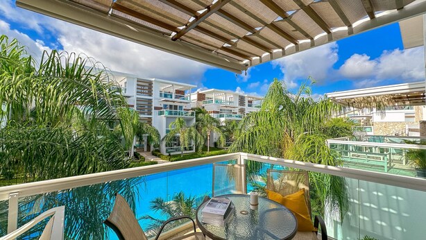 A rooftop pool area with a glass balustrade, a round glass table, and chairs. - Beautiful 2 BR Apartment With BBQ (Punta Cana)