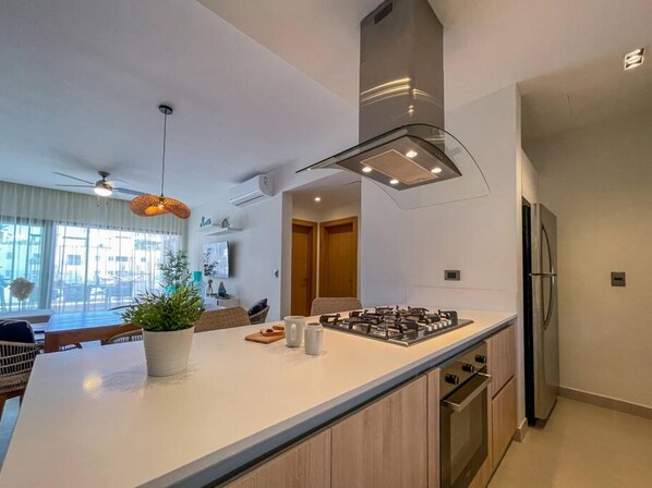 Una cocina moderna con una isla central, horno empotrado y electrodomésticos de acero inoxidable.