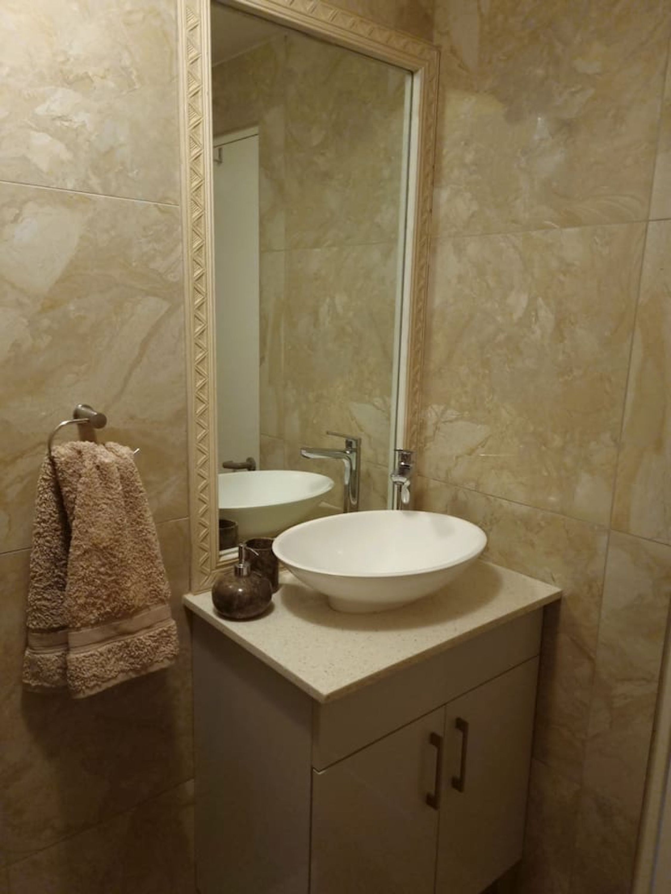 A bathroom with a large mirror, a white sink, and a towel rack.