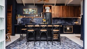 Une cuisine moderne aux couleurs noir et blanc, dotée d’un plan de travail en marbre, de tabourets de bar noirs et d’un ventilateur de plafond.