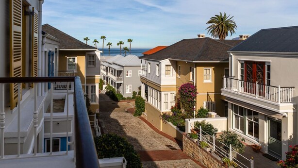 Un quartier résidentiel situé sur la côte, avec des maisons dotées de balcons, un chemin pavé et une vue sur l’océan.