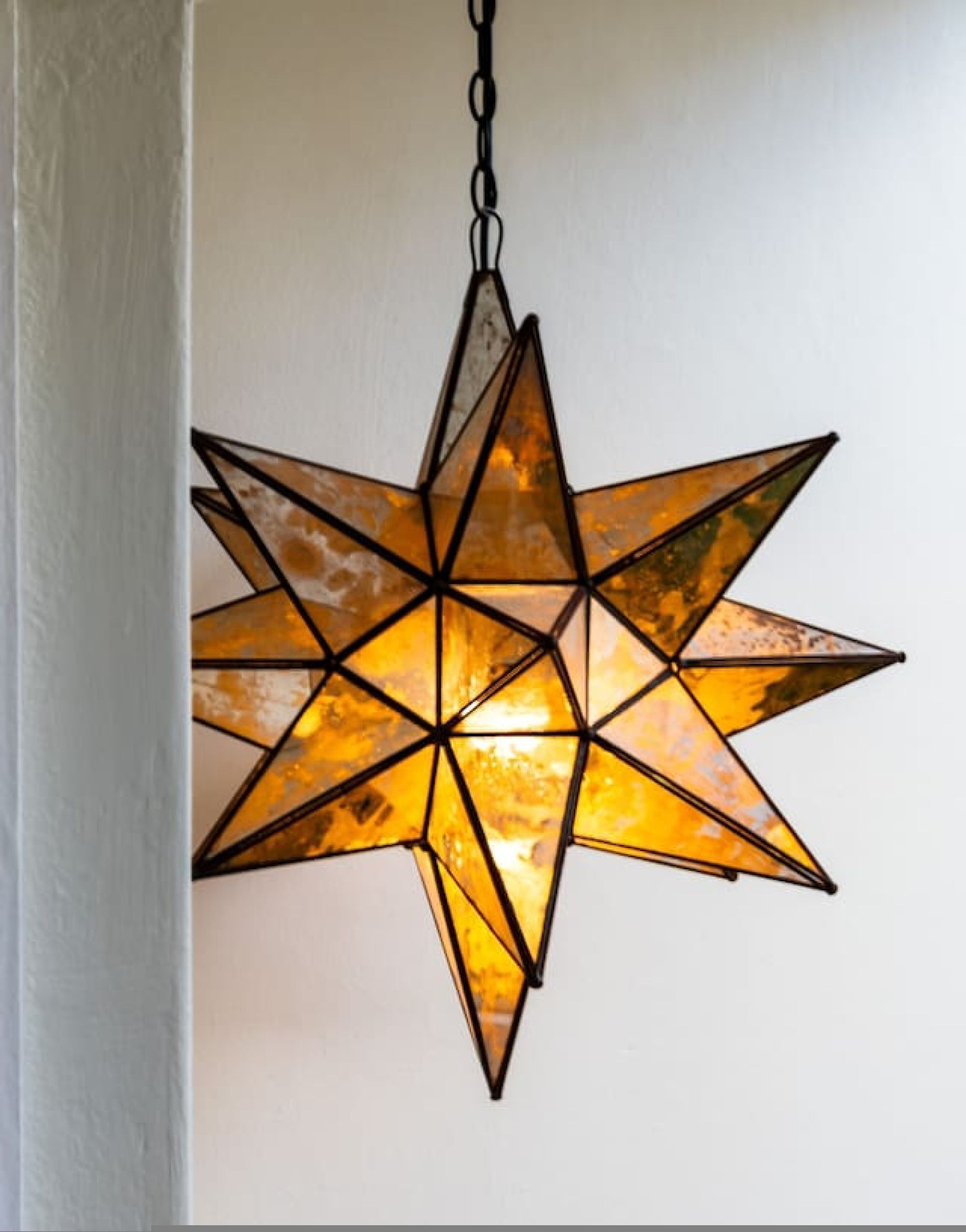 Lámpara colgante de forma geométrica en forma de estrella que emite una luz cálida.