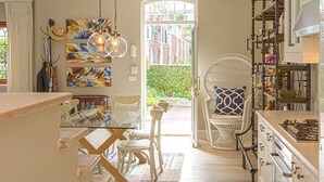 Una cocina con comedor, una silla de mimbre blanca y una mesa de vidrio.