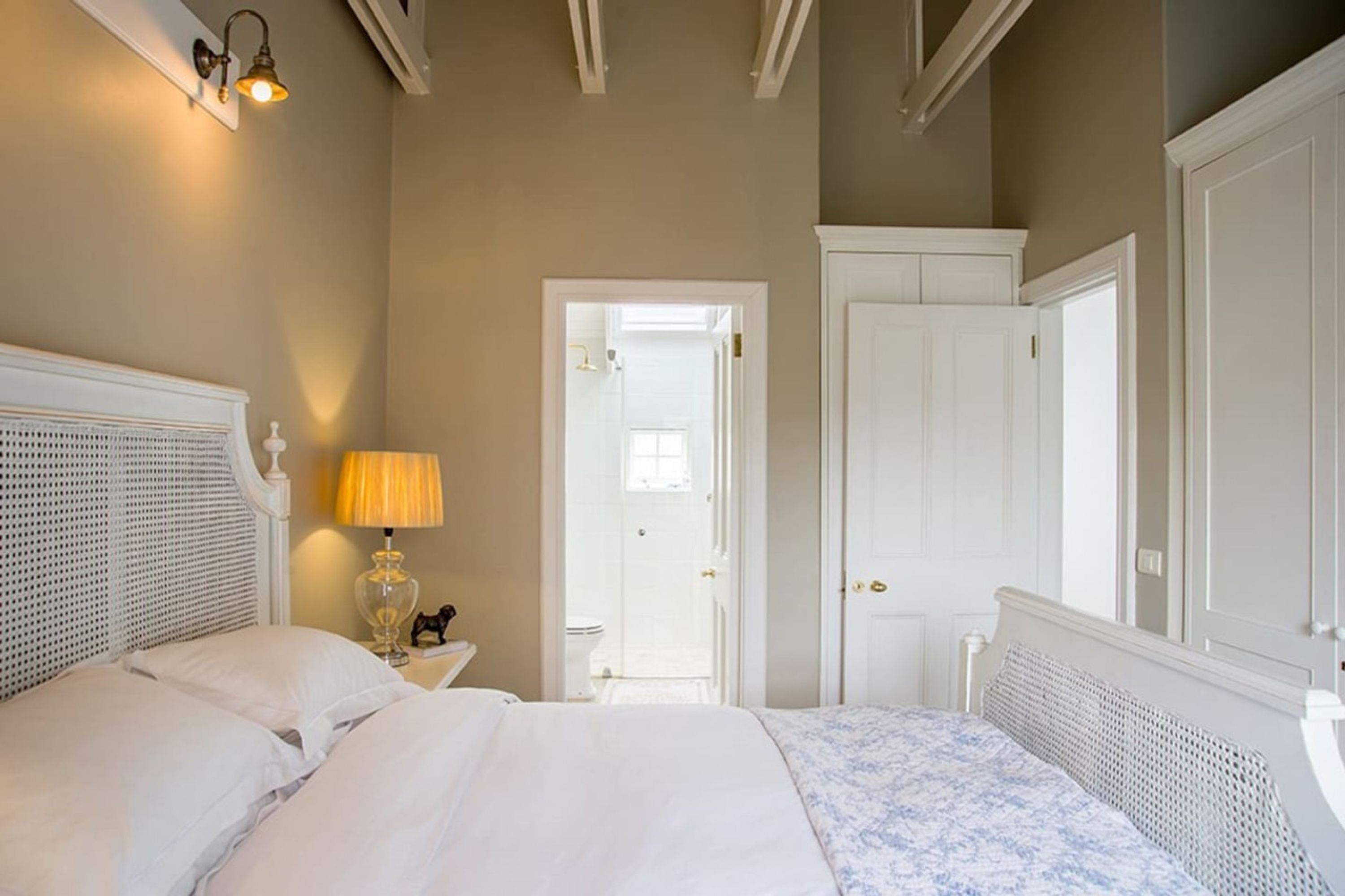 Ein Schlafzimmer mit Bett, Nachttischlampe und einer Tür zum Badezimmer.