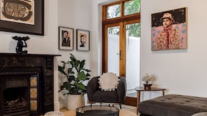 A living room with a fireplace, a potted plant, a round coffee table, a sofa, and artwork on the walls. - FIR Villa 3 Bedroom House Greenpoint (Cape Town)