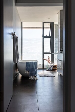 A modern bathroom with a freestanding bathtub, a large window, and a minimalist design.