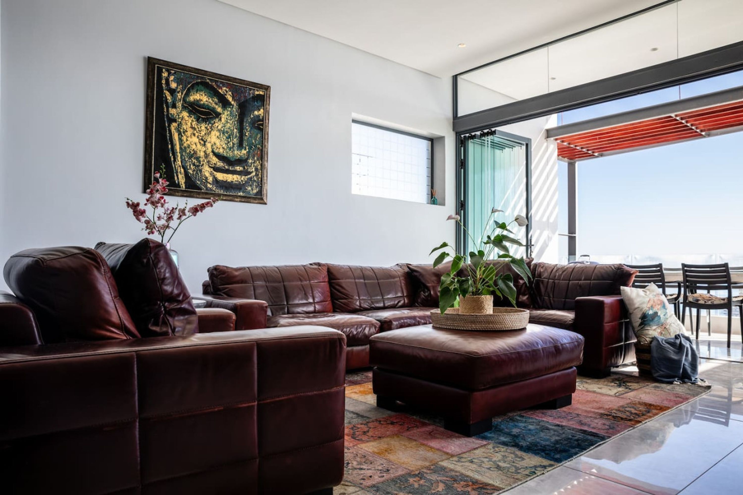 A modern living room with leather sofas, a coffee table with a plant, and a large abstract painting on the wall.