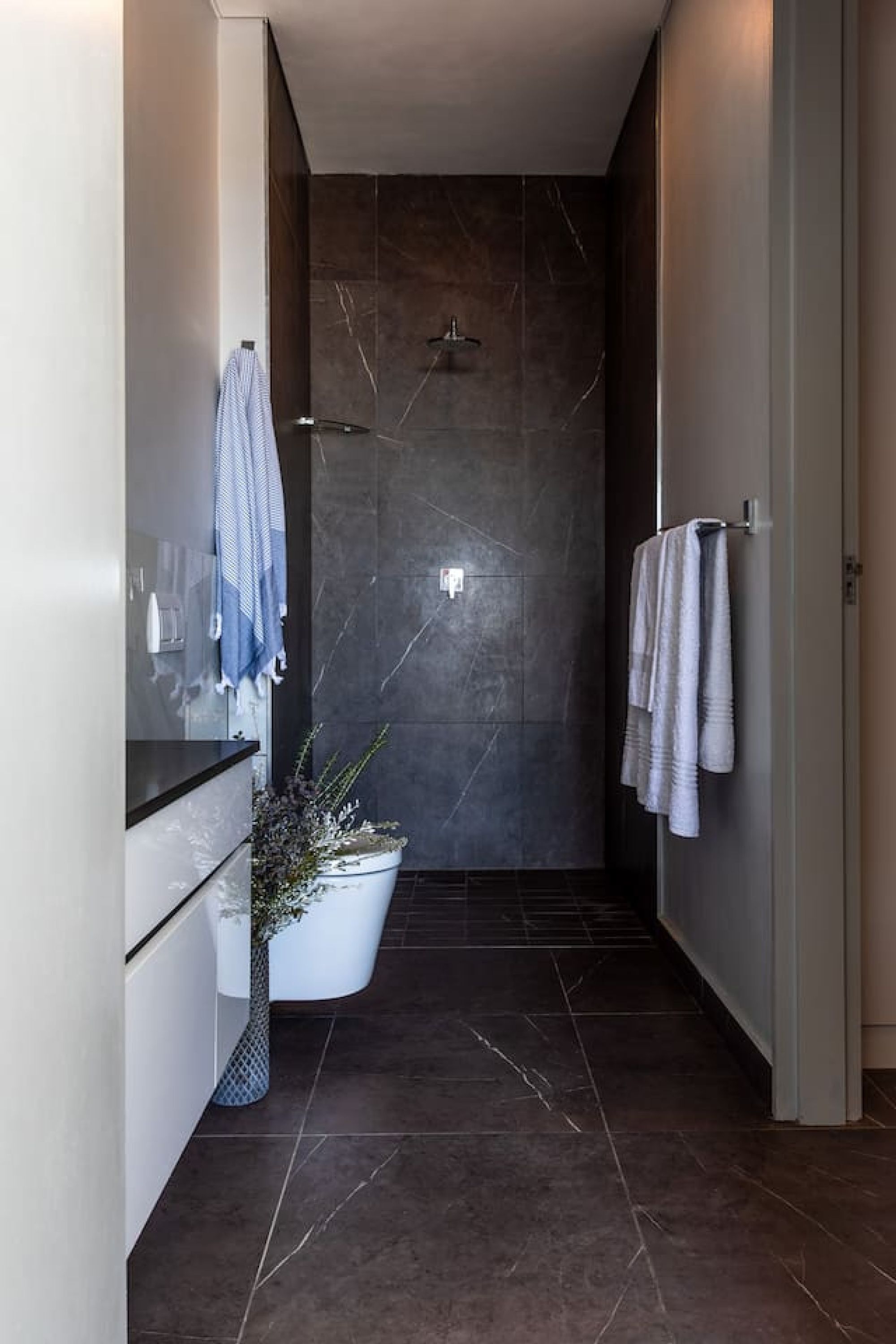 A modern bathroom with a shower, a white bathtub, and a towel rack.