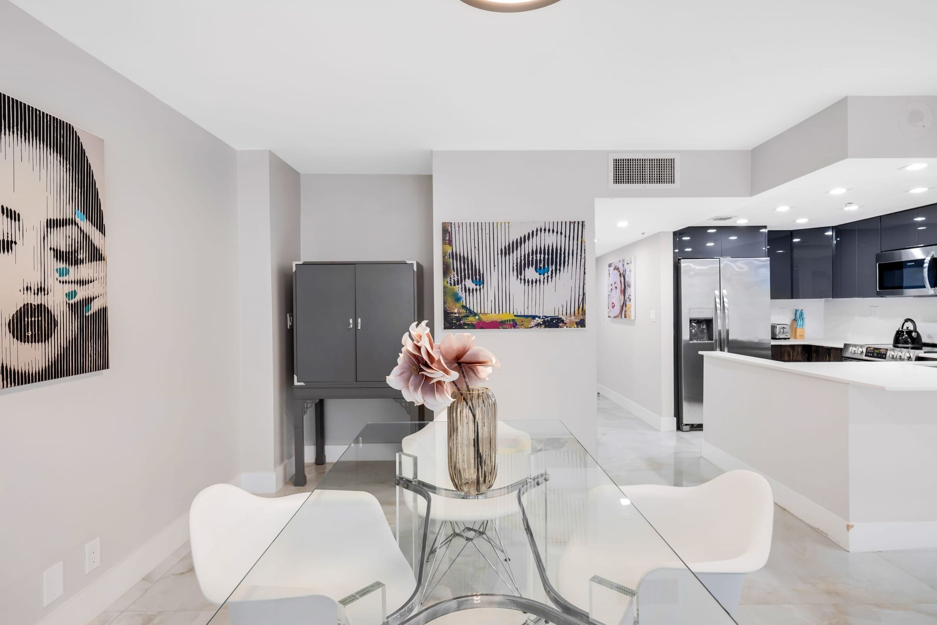 A modern kitchen with a central island, white cabinetry, and a stainless steel refrigerator.