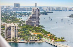 A coastal cityscape with high-rise buildings, a marina with sailboats, and a bridge connecting two areas. - City Vibes Ocean View Next to Art Basel (Miami)