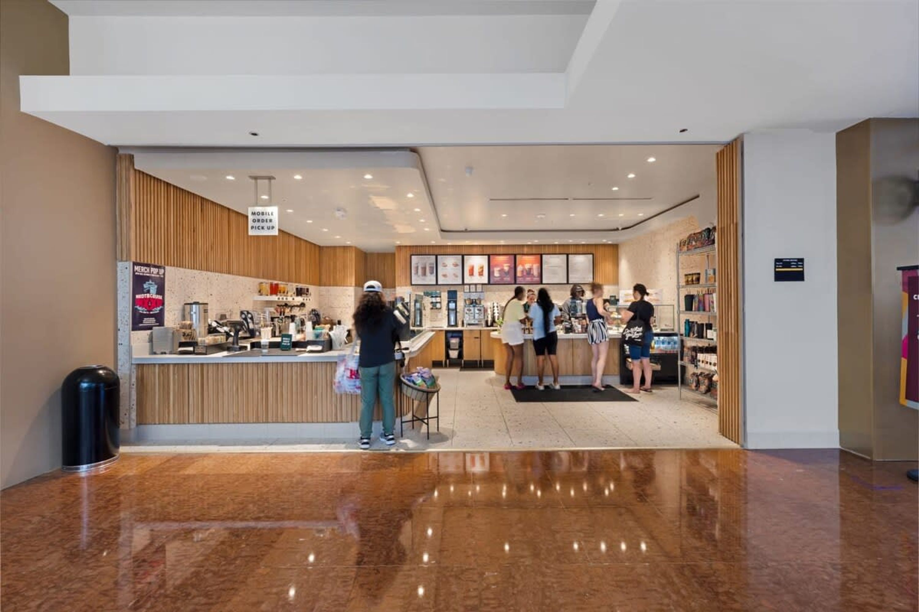 A modern interior with a polished marble floor, a counter area with a mobile ordering service, and a seating area with tables and chairs.