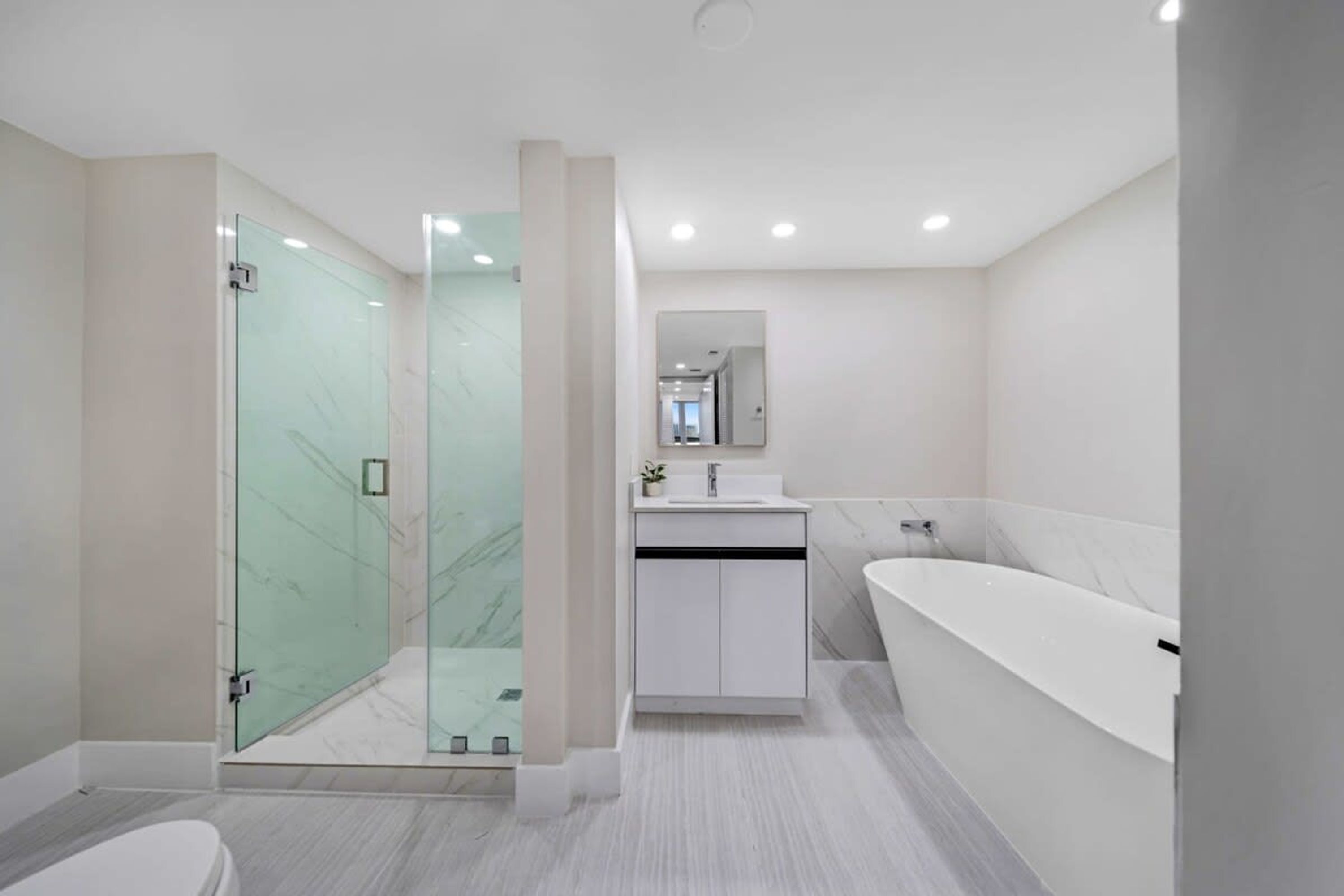 Un baño moderno con cabina de ducha de vidrio, bañera independiente y tocador minimalista.