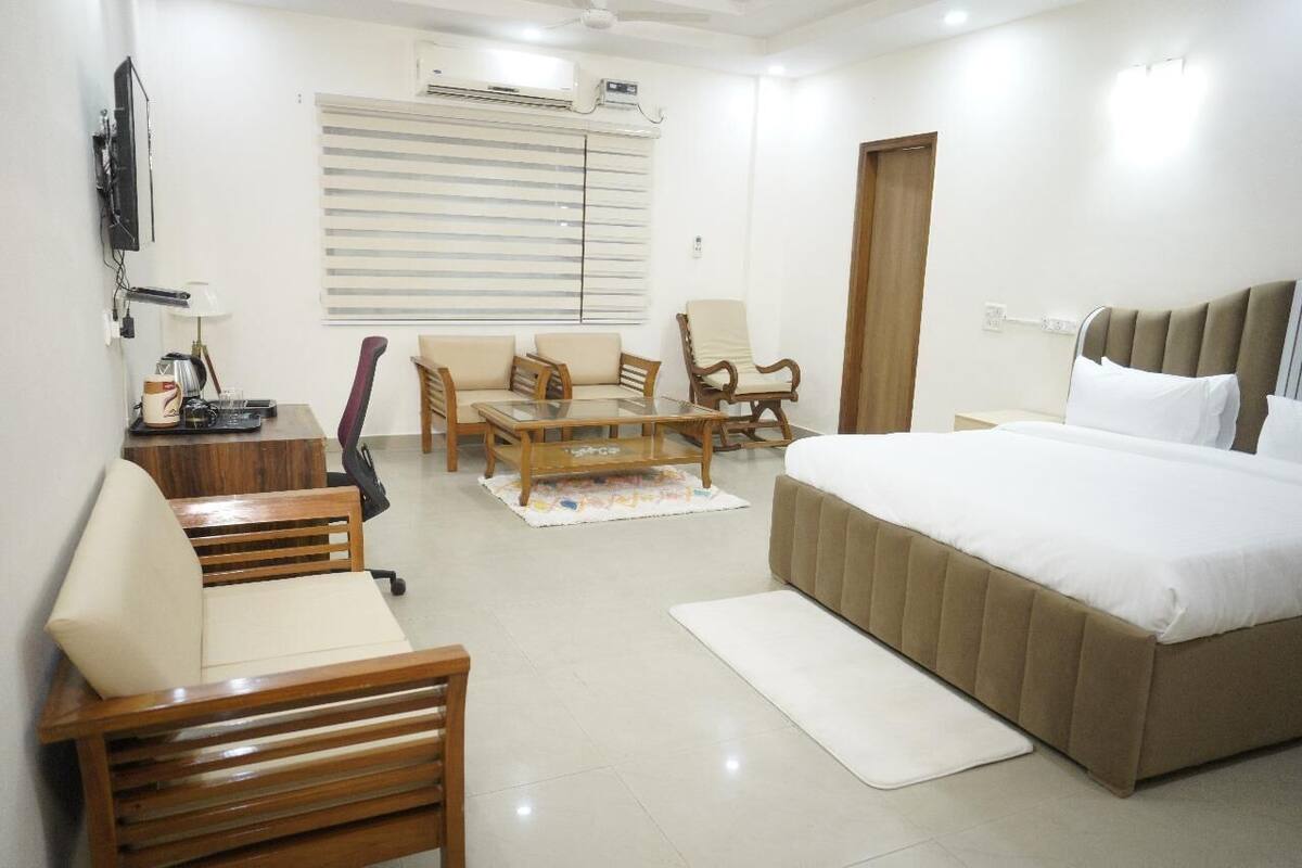A hotel room with a bed, a desk, a chair, and a sofa.