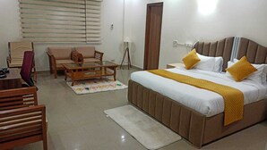 A hotel room with a bed, a sofa, a coffee table, and a chair. - Purple Tree Villa Delhi  (New Delhi)