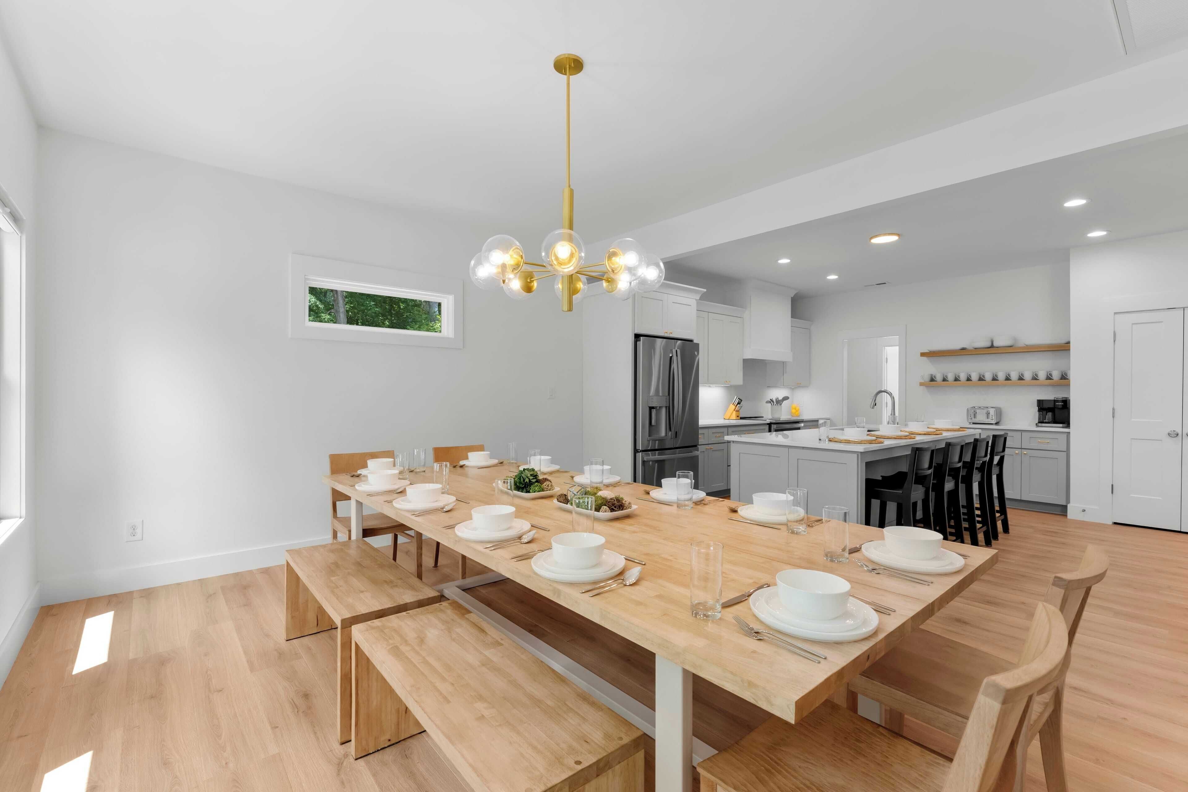 Una cocina moderna con armarios blancos, un refrigerador de acero inoxidable y una mesa de comedor de madera para seis personas.