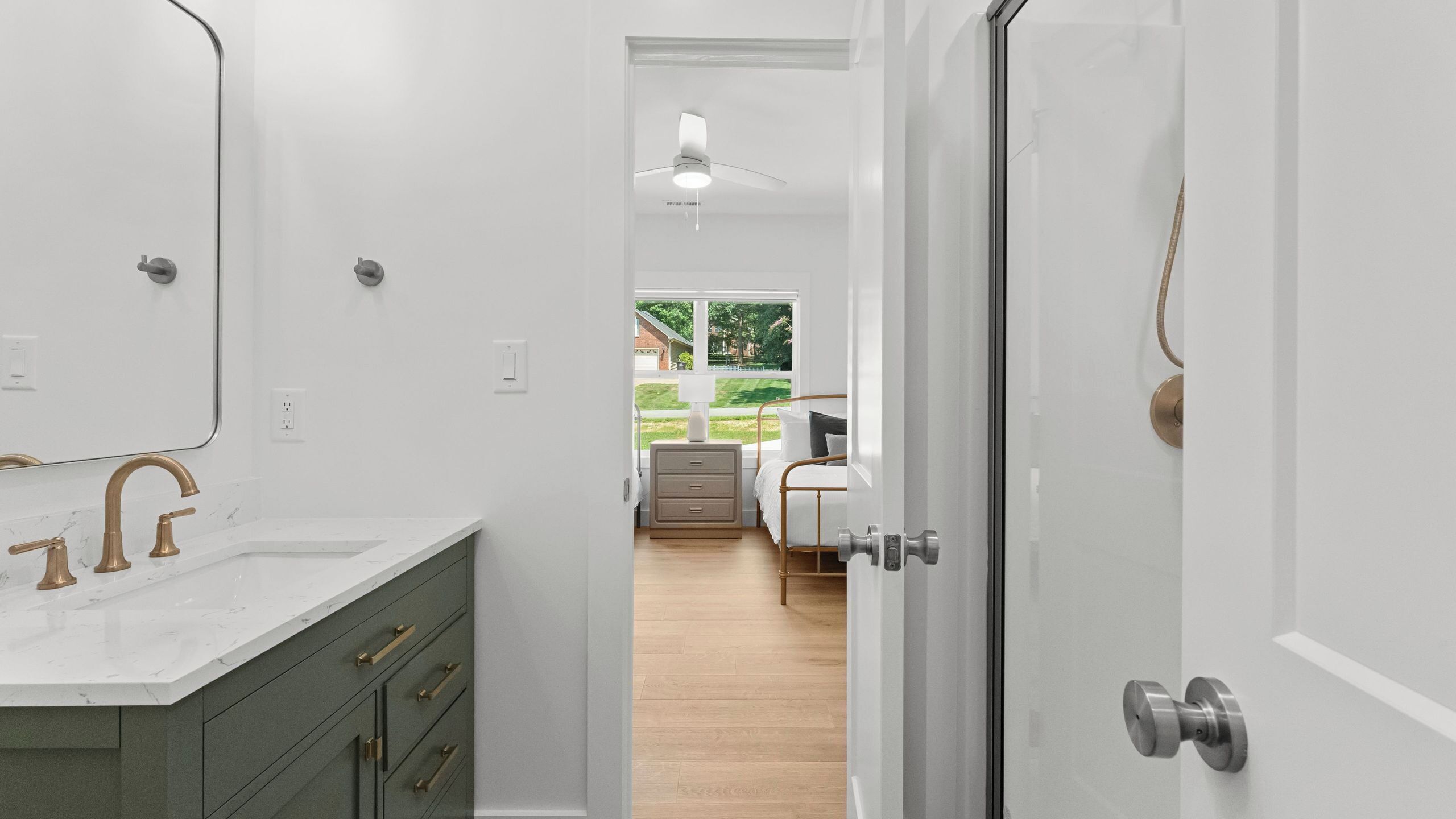 A bathroom with a white vanity, a mirror, and a ceiling fan.