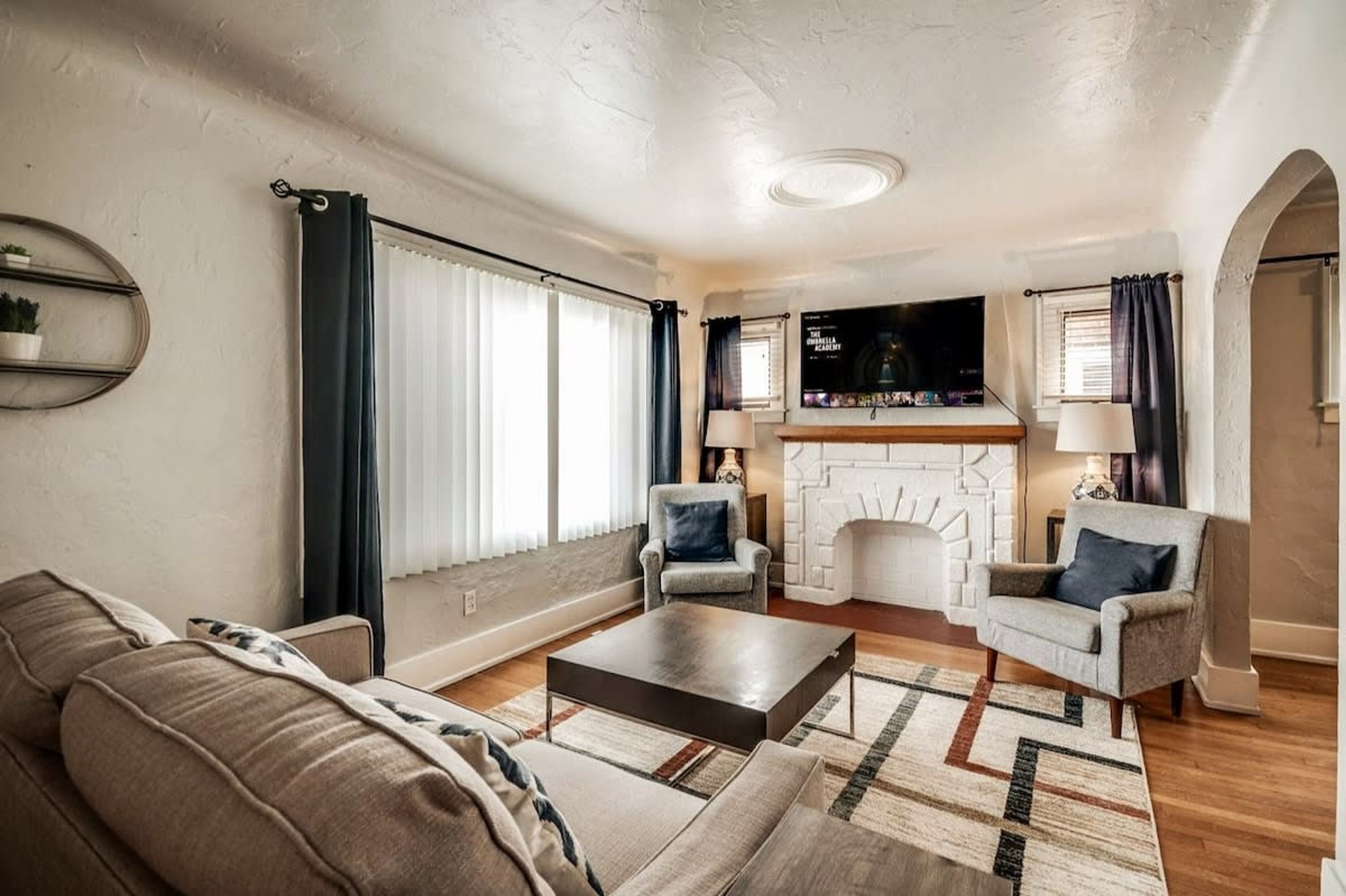 A living room with a sofa, armchairs, a coffee table, a fireplace, and a television.